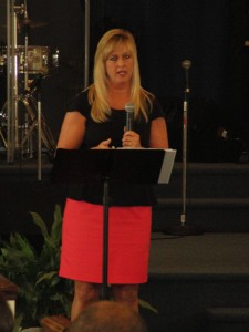 A woman is holding a microphone and speaking.